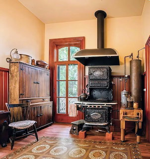 Vintage kitchen with black cast-iron stove, corrugated walls, wood door, and decorative tile floor