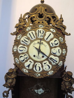Ornate antique baroque clock with carved wooden frame and large white numerals