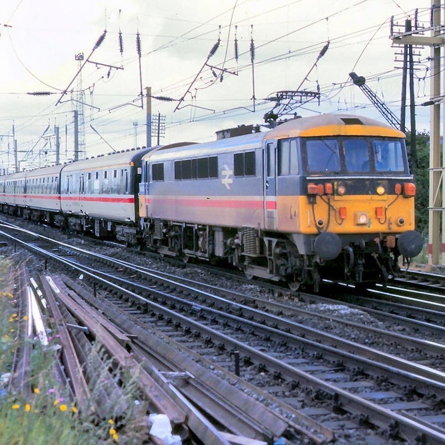 Silver and orange electric passenger train on railway tracks under overhead wires
