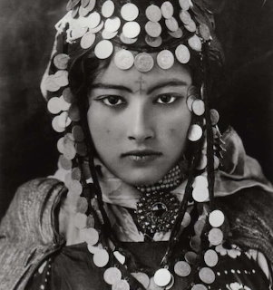Black and white portrait of a young woman wearing a traditional coin headdress and elaborate jewelry