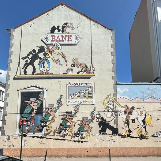 Colorful street mural featuring comic book characters painted on white building wall under blue sky