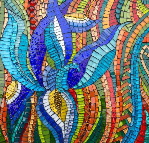 Abstract mosaic flower made of colorful glass tiles in blue, yellow, orange, red, and green on textured background
