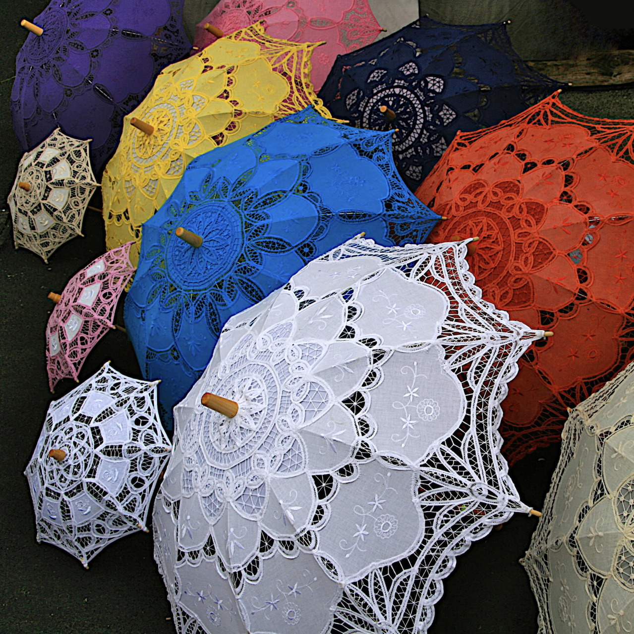 Colorful decorative lace umbrellas with intricate patterns arranged in an overlapping display