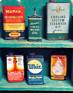 Six vintage product tins arranged on two turquoise painted shelves
