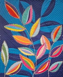 Colorful patchwork quilt with stylized leaves on a dark blue stitched background