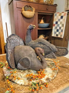 Vintage stuffed fabric turkey decorations with autumn leaves on table beside wooden cabinet