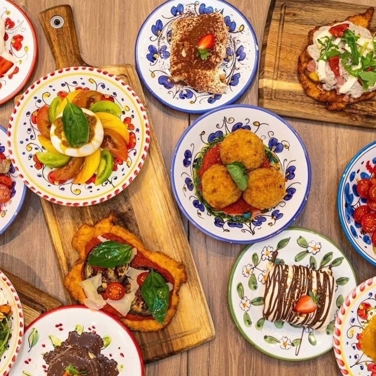 Overhead view of assorted brunch plates with toast, eggs, fruit, croquettes, and desserts on a wooden table