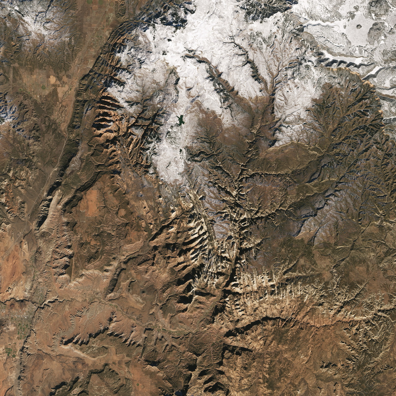 Aerial view of a rocky desert mountain region with canyons and patches of snow