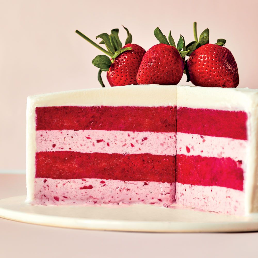 Slice of red and pink layered strawberry cake topped with fresh strawberries