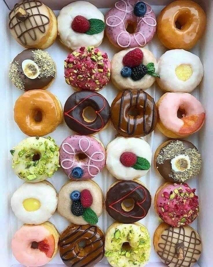 Top-down assortment of glazed and decorated donuts on a white background