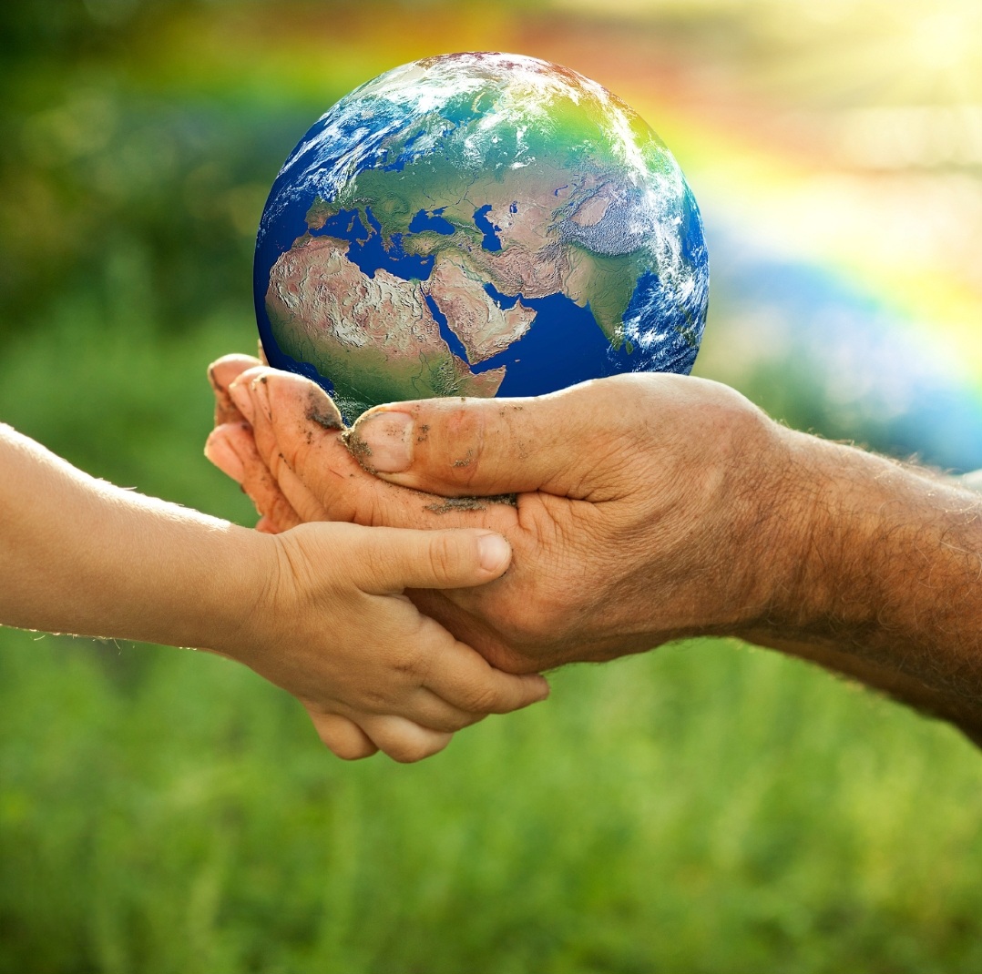 Hands passing a small Earth globe over green grass background