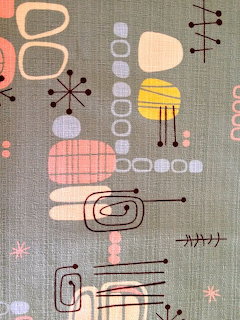 Mid-century modern atomic pattern with abstract shapes and starbursts on sage green fabric