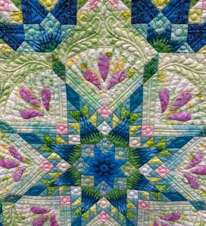 Colorful floral patchwork quilt block with blue star pattern and stitched fabric texture