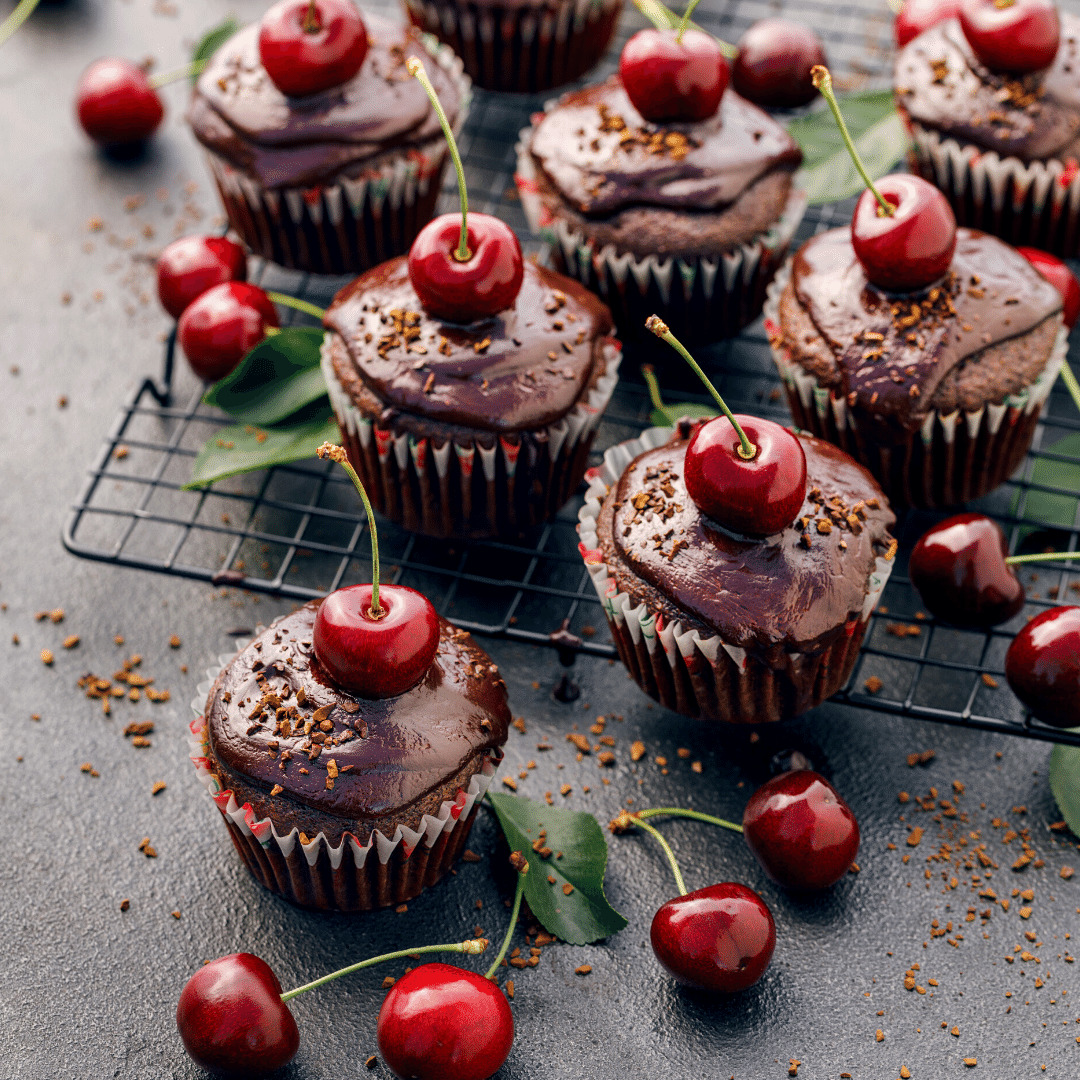 Chocolate cupcakes with frosting and cherry toppings on cooling rack