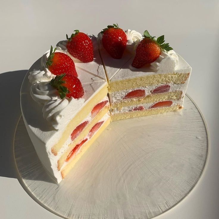 Sliced strawberry shortcake with cream layers and fresh strawberries on white plate