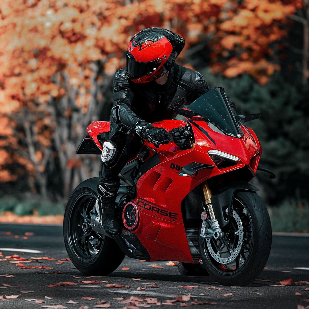 Black helmeted toy rider on red Ducati superbike with autumn foliage backdrop