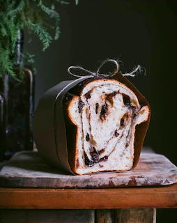 Sliced loaf of raisin bread on a wooden board against a dark background