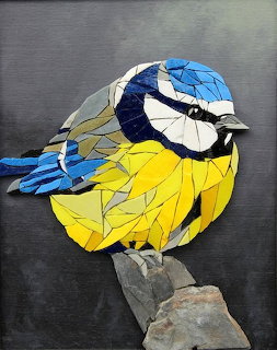 Mosaic art of a blue tit bird with yellow breast and blue wings perched on a stone