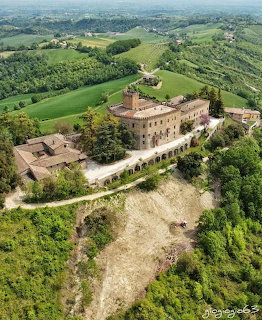 Aerial photograph of medieval castle on hiltop surrounded by green countryside in Italy