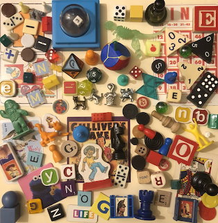 Flat lay of assorted vintage toys, dice, game pieces, letter blocks, and small figurines on a beige background