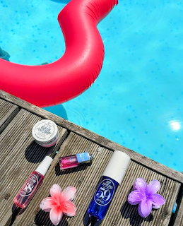 Sunscreen and beauty products on wooden pool deck with pink flamingo float and flowers