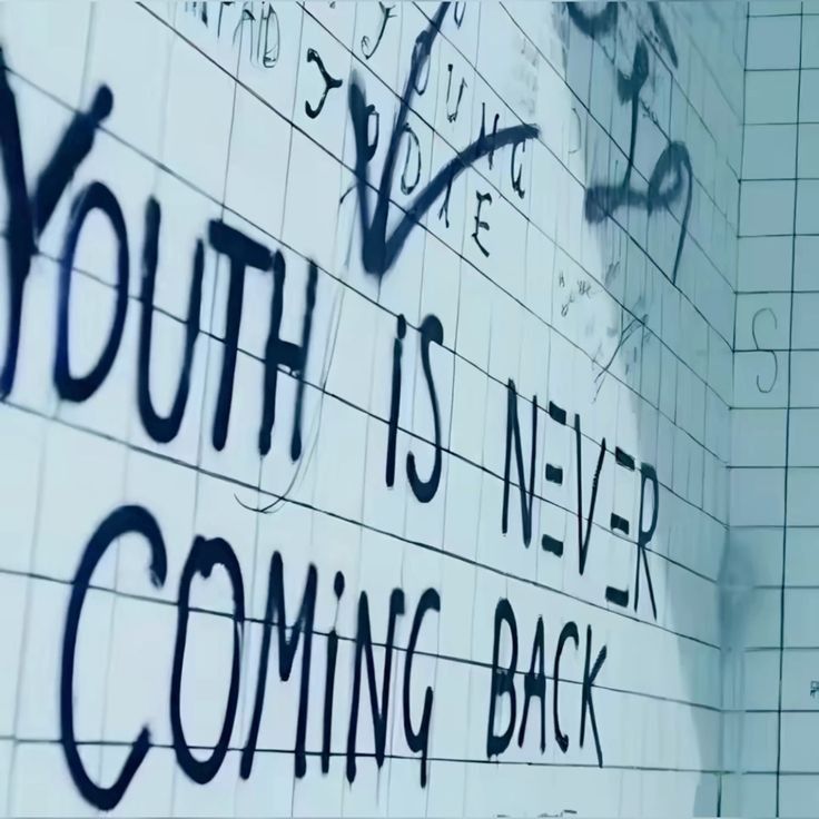 Graffiti on white tiled wall reading youth is never coming back with various tags and drawings
