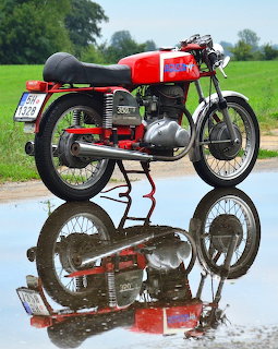 Red and black MV Agusta 350 Elettronica vintage motorcycle on reflective surface outdoors