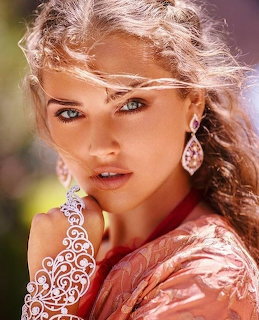 Close-up portrait of a woman with curly hair, dangling earrings, and a lace glove