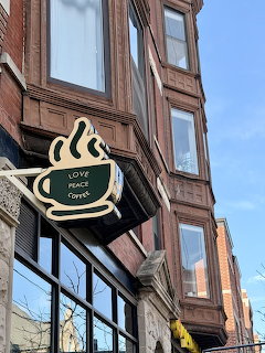 Coffee cup sign on a brick building exterior with tall windows and blue sky