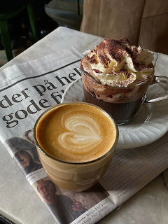 Latte with heart foam art and hot cocoa with whipped cream on a newspaper