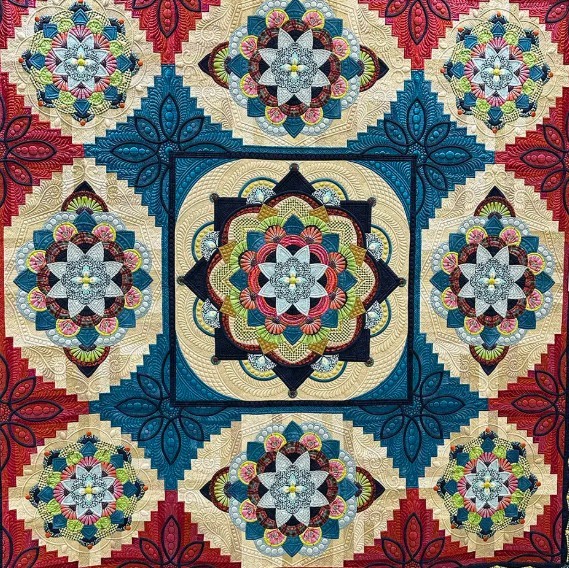 Symmetrical patchwork quilt with ornate geometric medallions and colorful floral patterns on burgundy background