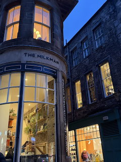 The Milkman cafe exterior at dusk on a narrow Edinburgh street with warmly lit windows