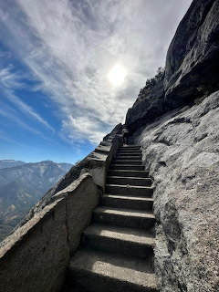 Stone stairway on Moro Rock climbing beside a granite cliff under a bright cloudy sky
