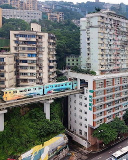 Monorail train passing between tall apartment buildings on a hillside in Chongqing, China
