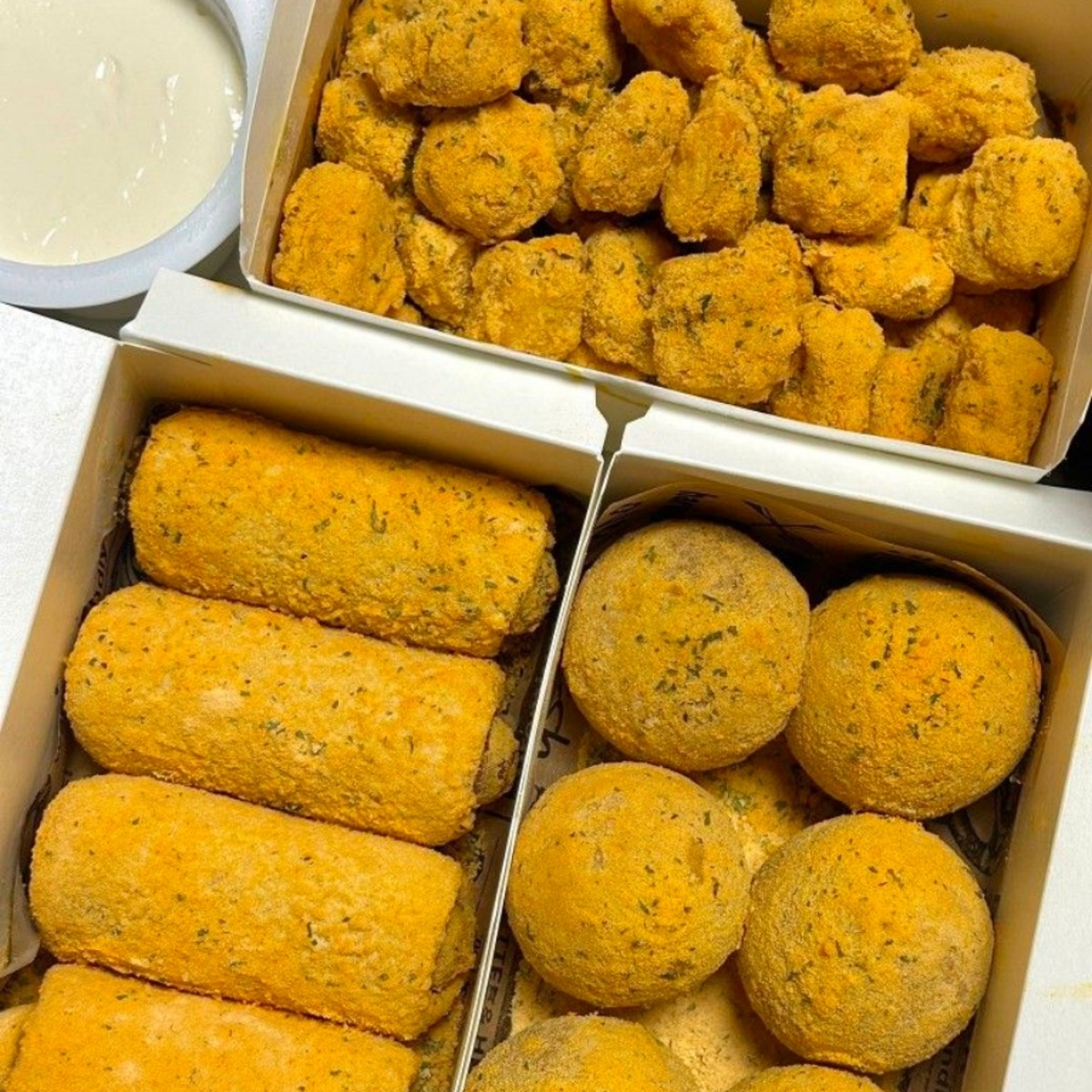 Golden fried Korean street snacks in white boxes with sauce
