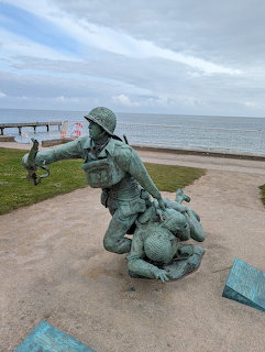 Bronze statue of two soldiers at a coastal memorial overlooking the ocean