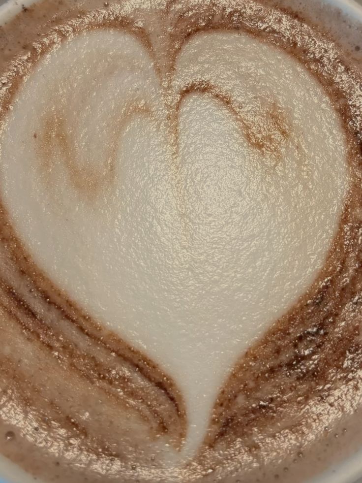 Latte with heart-shaped foam art in a white cup