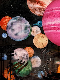 Collage art showing various colorful planets including pink, orange, and blue spheres against a black starry sky