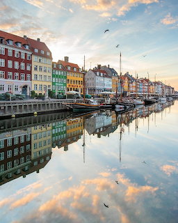 Colorful buildings and boats reflected in Nyhavn canal in Copenhagen at sunset