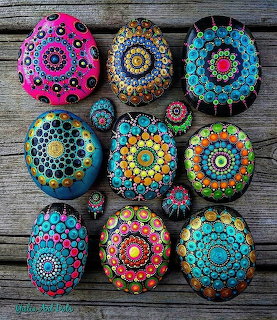 Collection of hand-painted stones with colorful mandala dot patterns on wooden surface
