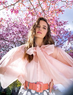 Woman in pink blouse standing under cherry blossom trees in full bloom