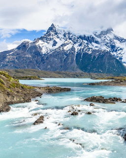 Turquoise river rapids with snow-capped mountains in Torres del Paine National Park, Chile.