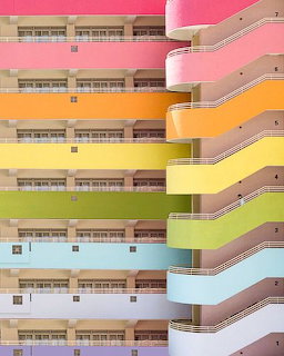 Multi-story building with rainbow-colored wavy horizontal balconies in pastel shades
