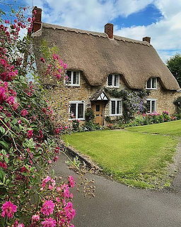 Thatched cottage with pink flowers and green lawn