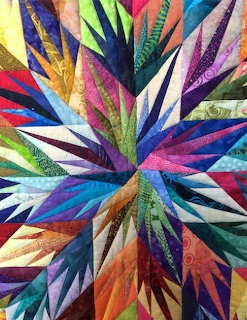 Colorful crazy quilt with irregular fabric patches and decorative embroidery stitching.