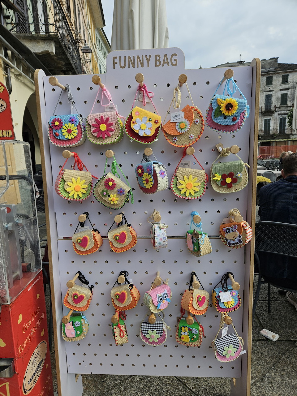 Display of colorful novelty bag charms with cartoon faces and emoji designs on outdoor rack