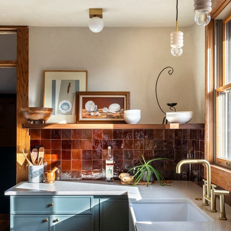 Vintage kitchen with blue-green cabinets, brown tiled backsplash, white countertop, and brass fixtures