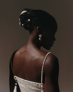 Woman in profile wearing a white gown with pearl straps and drop earrings