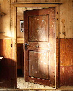 Old weathered wooden door with two panels in a rustic wood-paneled room with natural light