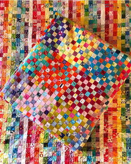 Colorful patchwork quilts with checkerboard patterns in rainbow hues layered over striped background